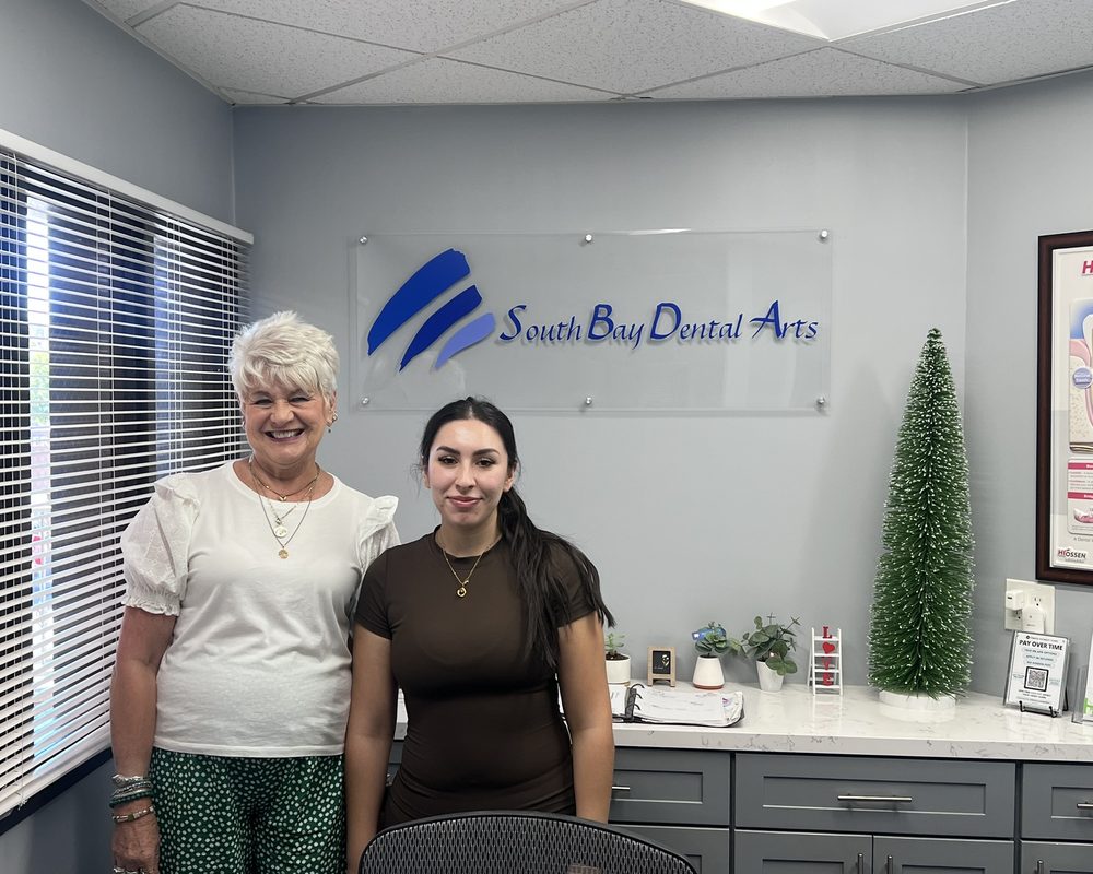 Joyce Van Berkum and a team member in front of the South Bay Dental Arts sign
