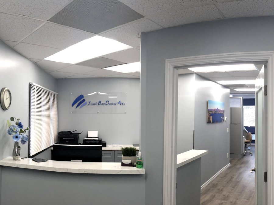 Reception desk at South Bay Dental Arts with lobby sign
